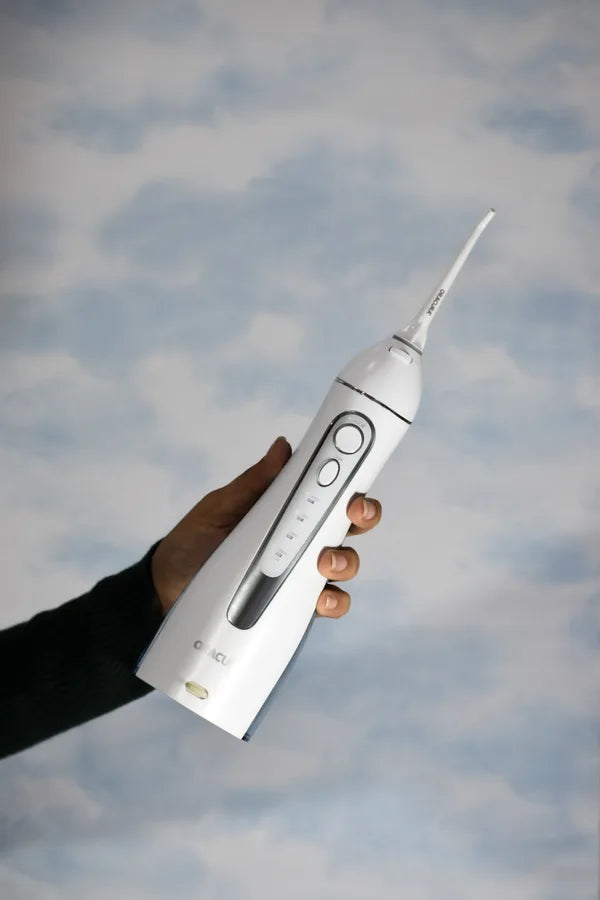 An ORACURA customer with their water flosser or electric toothbrush