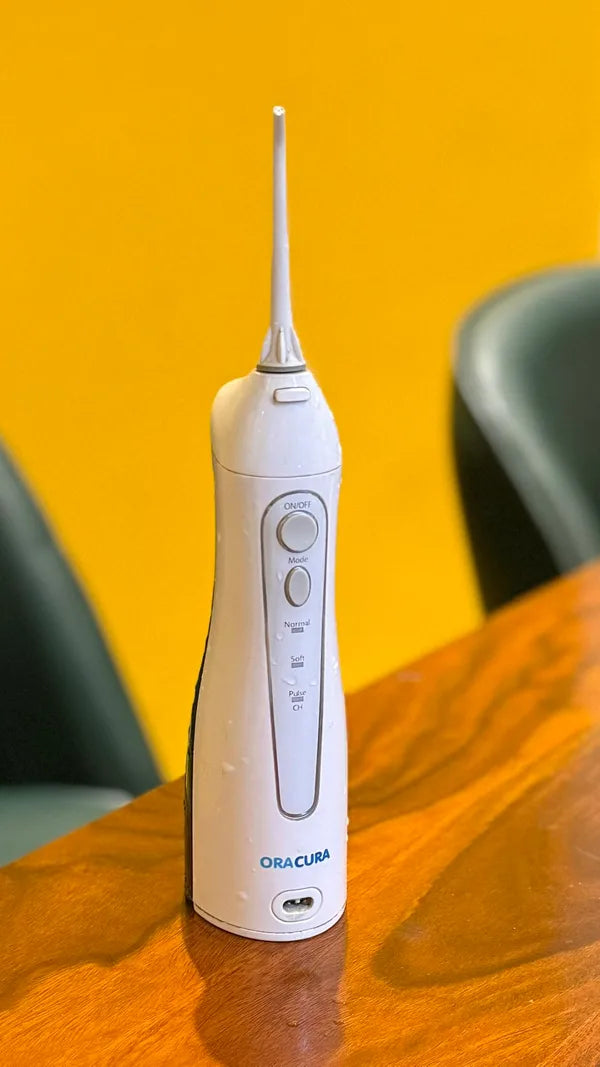 An ORACURA customer with their water flosser or electric toothbrush